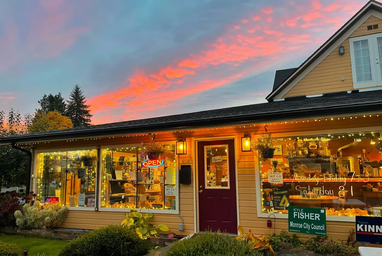 Monroe Coffee Co. storefront aglow with string lights under a pink sunset sky